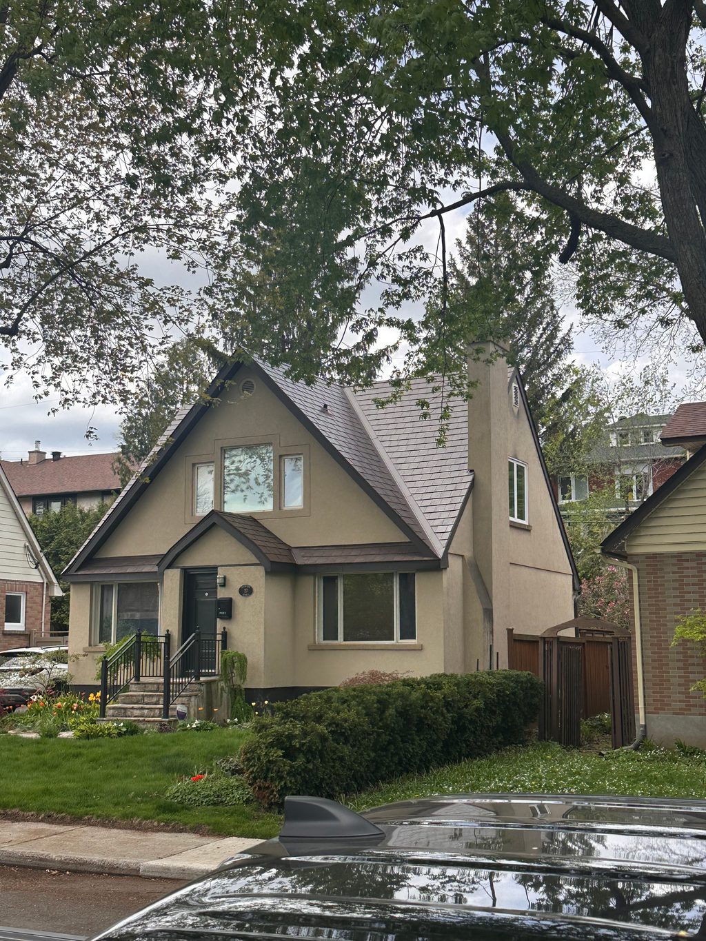 1.5-storey Tudor-style home in Ottawa with Interlock Colonial Brown aluminum slate metal roofing featuring steep complex gables and chimney.