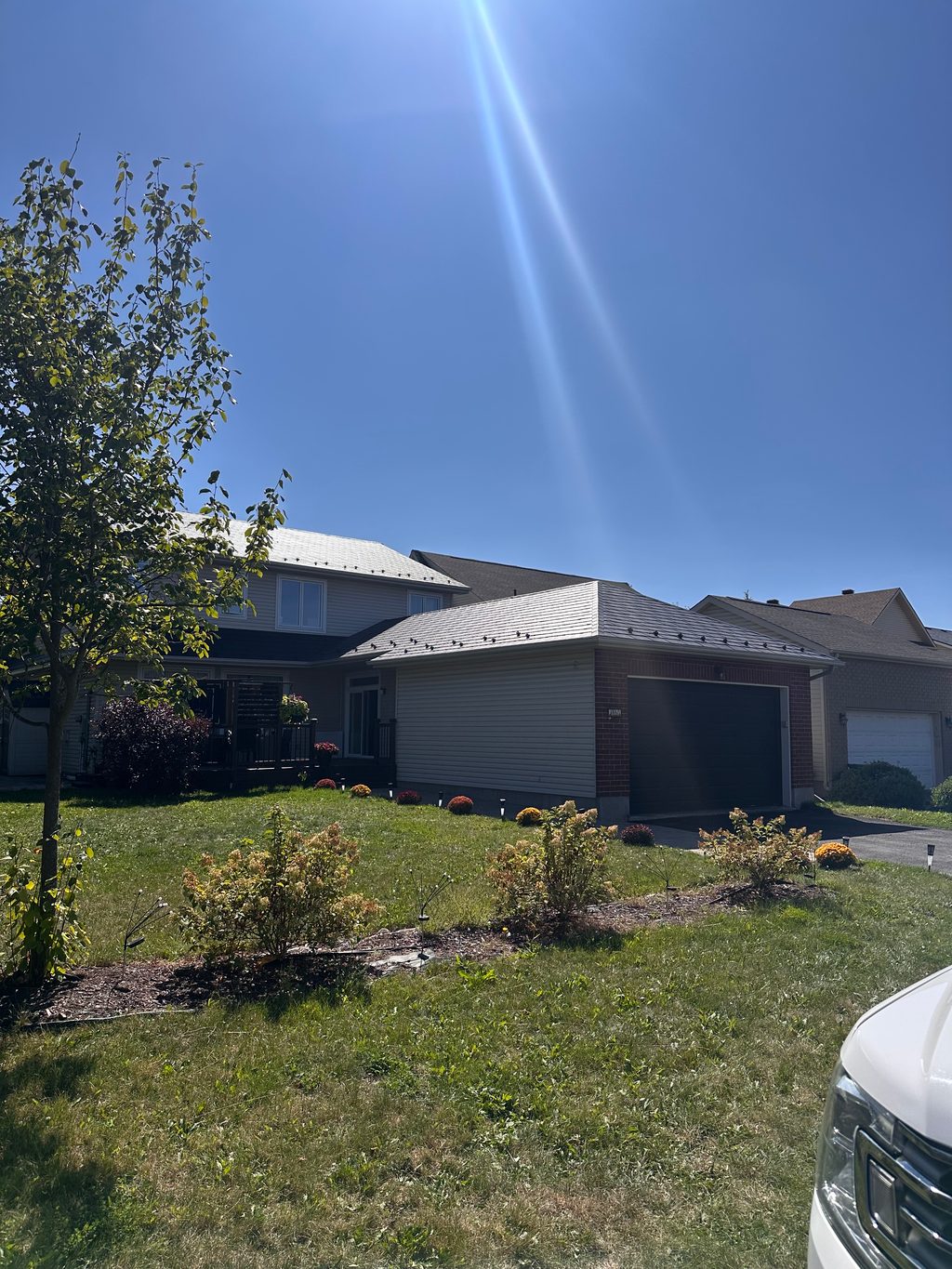 Two-storey suburban home with Interlock black aluminum slate metal roofing across multi-hip profiles, brick and vinyl siding, Ottawa ON.