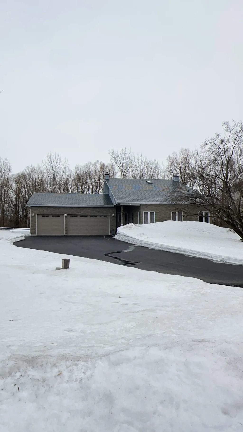 Black Interlock Slate aluminum roof on a rural home with a grey metal roof and attached garage in, Navan, Ontario