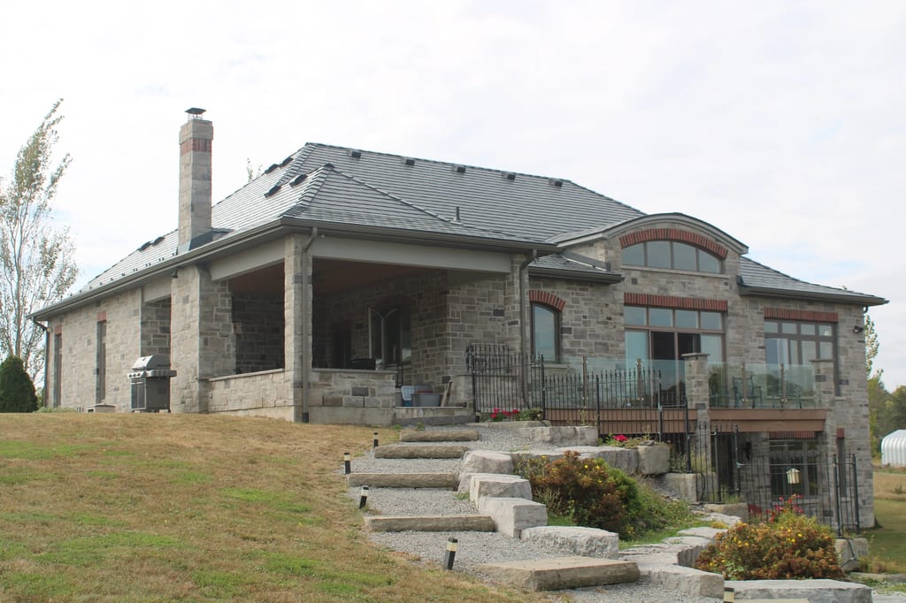 Deep Charcoal Interlock Slate aluminum roof on a modern home with a stone facade on a rural property, Picton, Ontario
