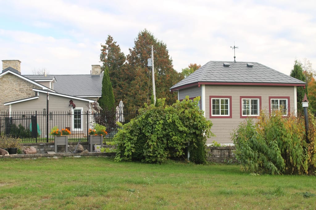 Deep Charcoal Interlock Slate aluminum roof on a tan home with a grey roof in a forested area, Carleton Place, Ontario