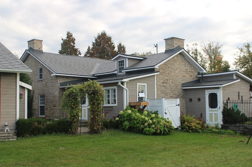 Deep Charcoal Interlock Slate aluminum roof on a tan home with white trim and a metal roof in a rural, Carleton Place, Ontario