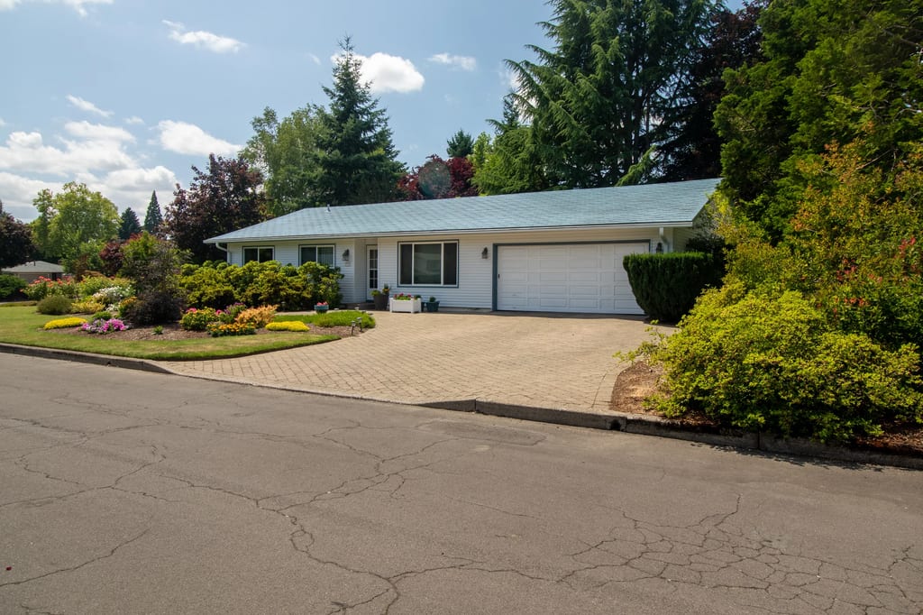Charcoal Grey Interlock Shingle aluminum roof on a white home with a metal roof among tall trees, Hillsboro, Oregon