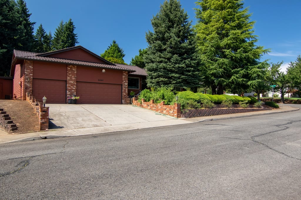 Colonial Brown Interlock Tile aluminum roof on a Colonial brown roof on a two-storey home among tall pines, Salem, Oregon