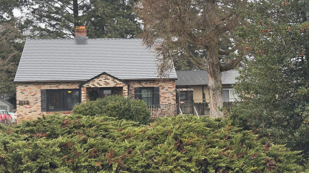 Black Interlock Cedar Shingle aluminum roof on a brown one-storey cottage with a metal roof in a forested, Hood River, Oregon