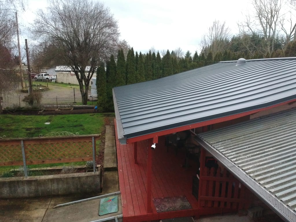 Deep Charcoal Interlock Standing Seam aluminum roof on a red home with a metal roof among tall trees, Scio, Oregon