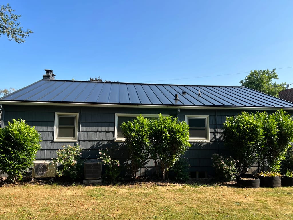 Black Interlock Standing Seam aluminum roof on a dark home with a metal roof among greenery in a, Portland, Oregon