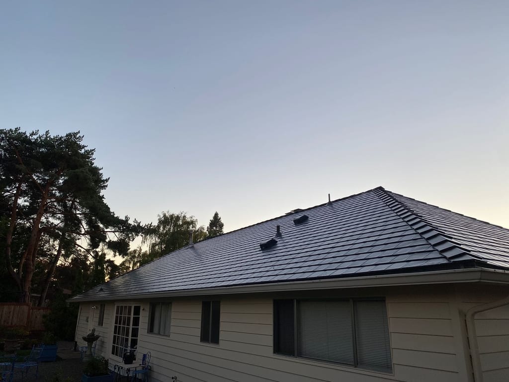 Black Interlock aluminum slate metal roof on a single-story ranch home, photographed at twilight from the rear-left elevation in Portland, OR.