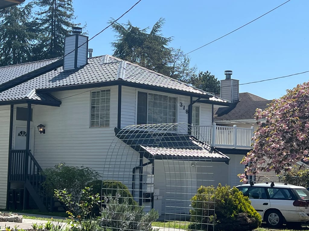 Charcoal Grey Interlock Tile aluminum roof on a white two-storey home with a metal roof in a suburban, Seattle, Washington