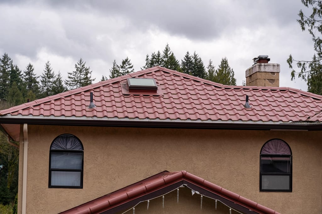 Tile Red Interlock Tile aluminum roof on a tan house with red tile roof and red trim in a forested, Woodinville, Washington