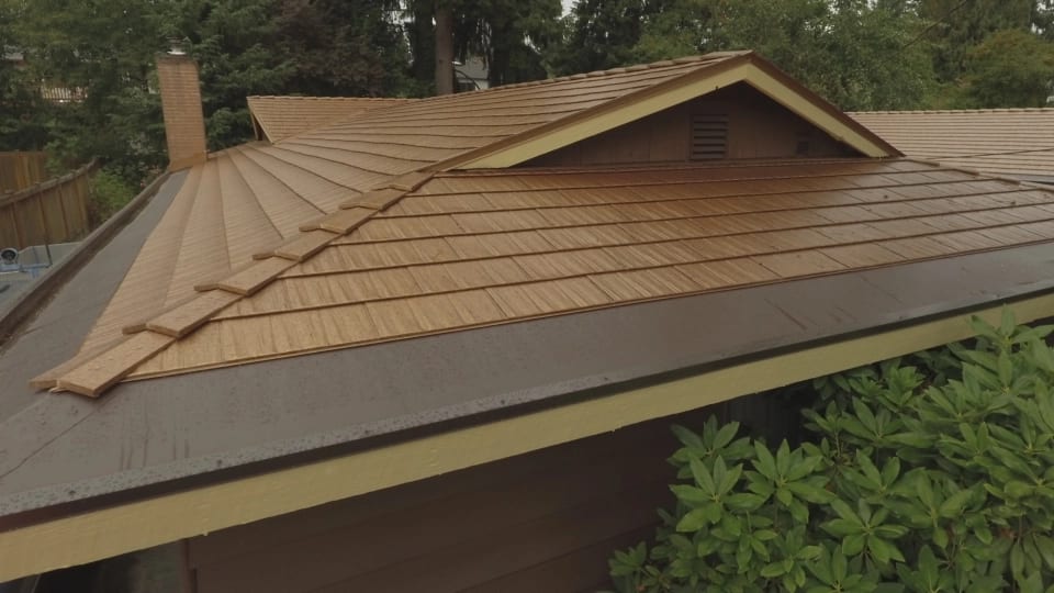 Aged Copper Interlock Cedar Shingle aluminum roof on a brown house with a metal roof among green trees in a, Bellevue, Washington