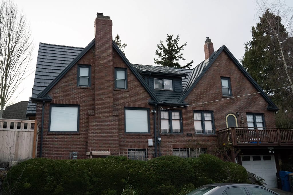 Deep Charcoal Interlock Shake aluminum roof on a red brick two-storey home with dormers in a forested, Seattle, Washington