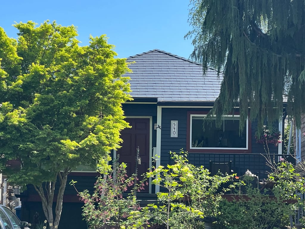 Deep Charcoal Interlock Slate aluminum roof on a dark brown one-storey Craftsman home among tall trees, Seattle, Washington