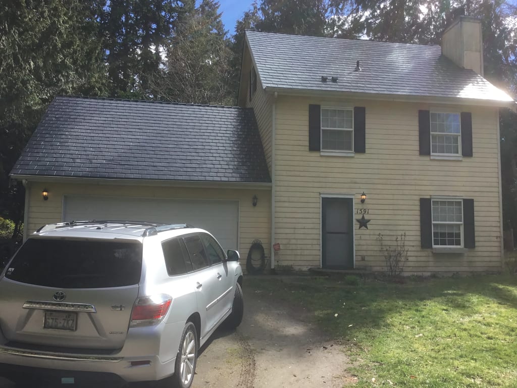 Black Interlock Slate aluminum roof being installed on a two-storey colonial home with a grey metal roof and black, Poulsbo, Washington