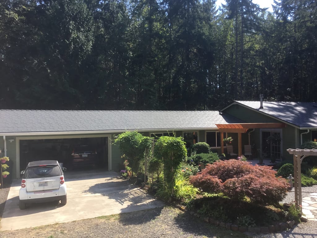 Deep Charcoal Interlock Slate aluminum roof on a green single-storey home with a metal roof among tall, Poulsbo, Washington
