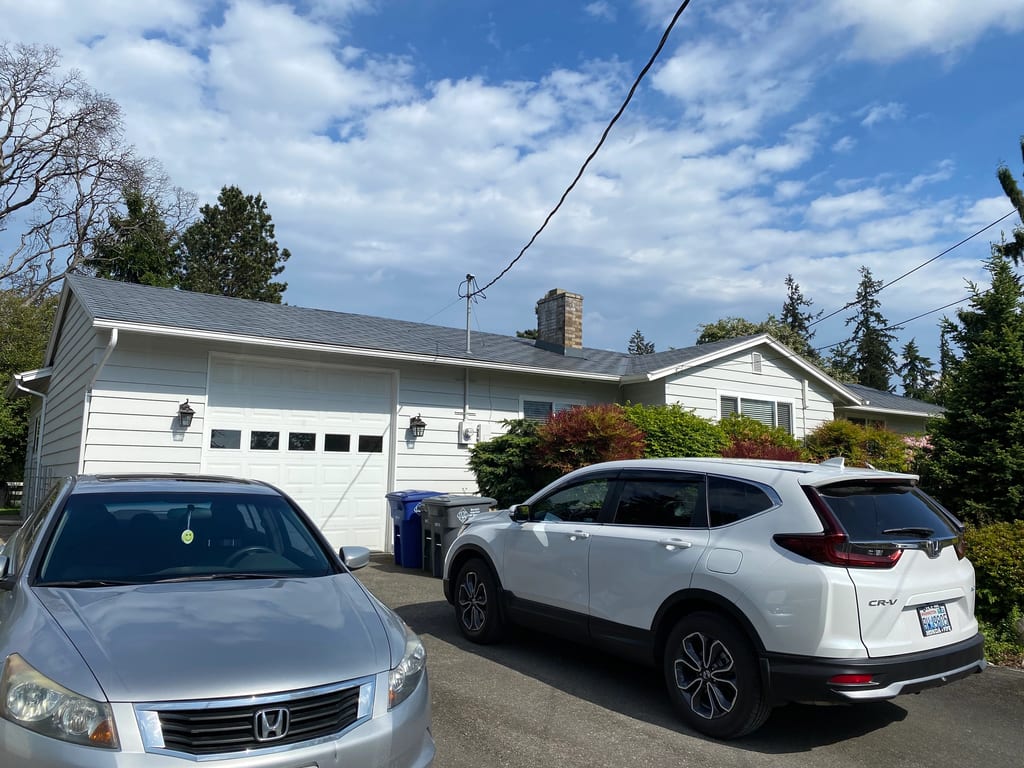 Deep Charcoal Interlock Slate aluminum roof on a white one-storey home with a metal roof among trees, Tacoma, Washington