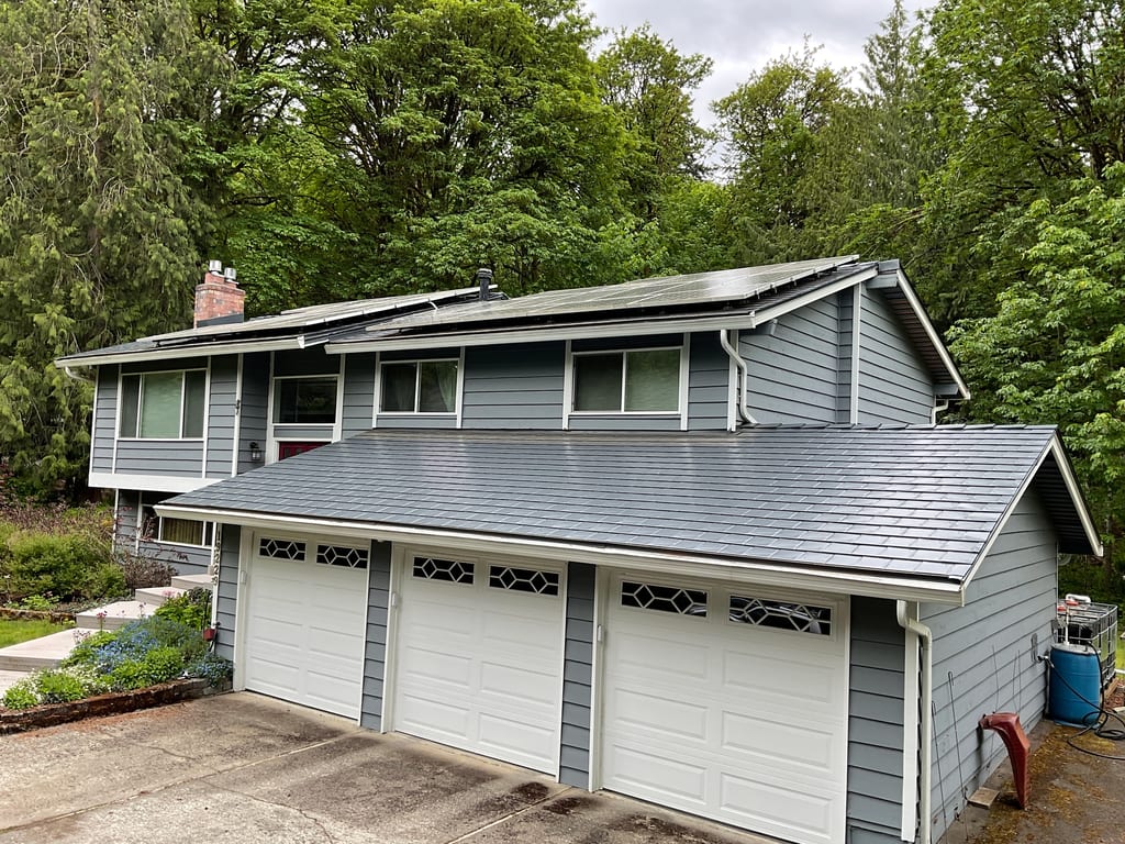 Deep Charcoal Interlock Slate aluminum roof on a grey two-storey home with dormers among tall pines, Woodinville, Washington