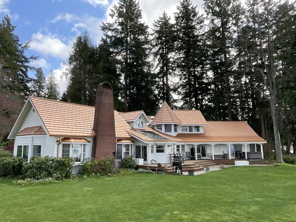 Copper Penny Interlock Shake aluminum roof on a white cottage with a copper penny metal roof among tall, Bremerton, Washington