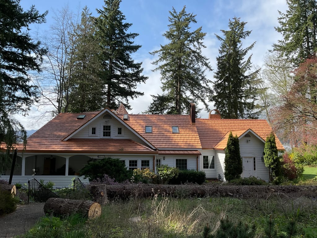 Copper Penny Interlock Shake aluminum roof on a white home with a red roof among tall trees, Bremerton, Washington