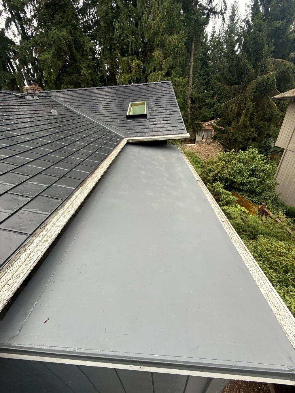 Black Interlock Slate aluminum roof on a black single-family home with dormers among tall, Redmond, Washington
