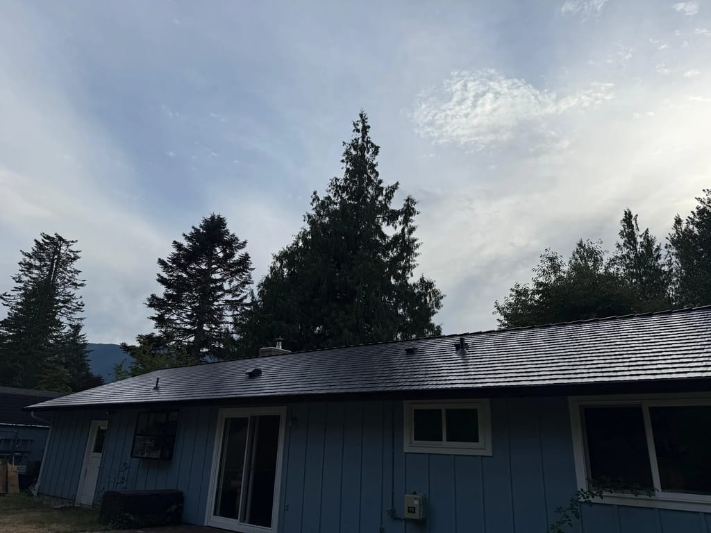 Black Interlock Cedar Shingle aluminum roof on a blue single-story ranch with a metal roof in the woods, North Bend, Washington