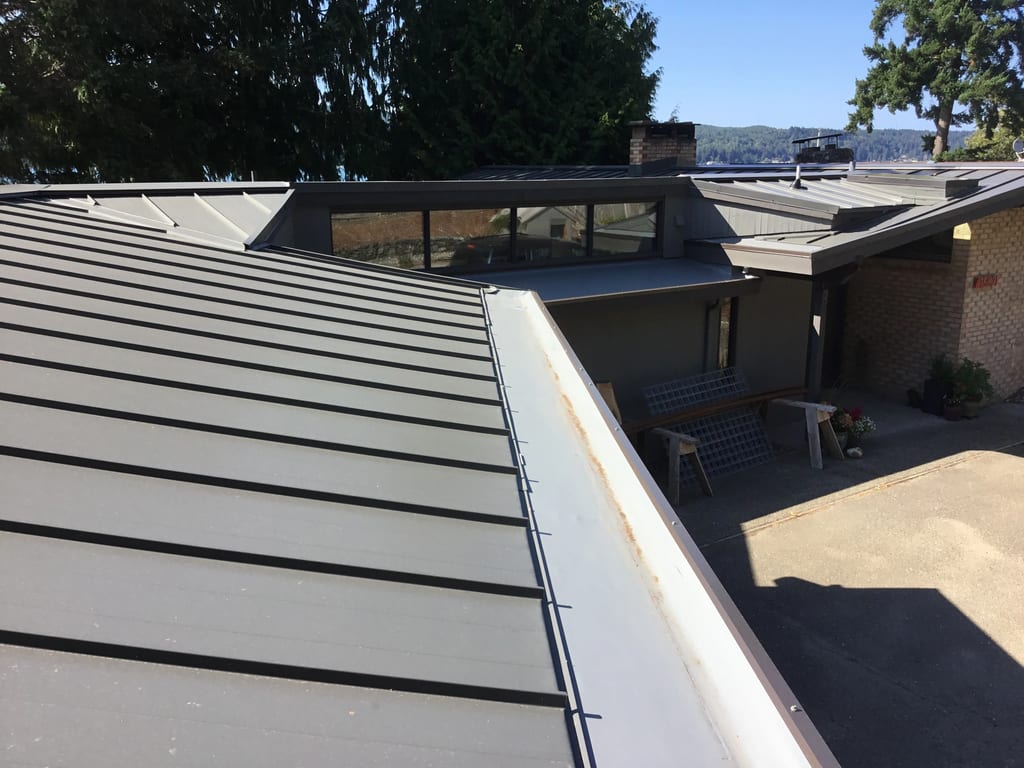Musket Grey Interlock Standing Seam aluminum roof on a beige home with a metal roof near a body of water, Belfair, Washington