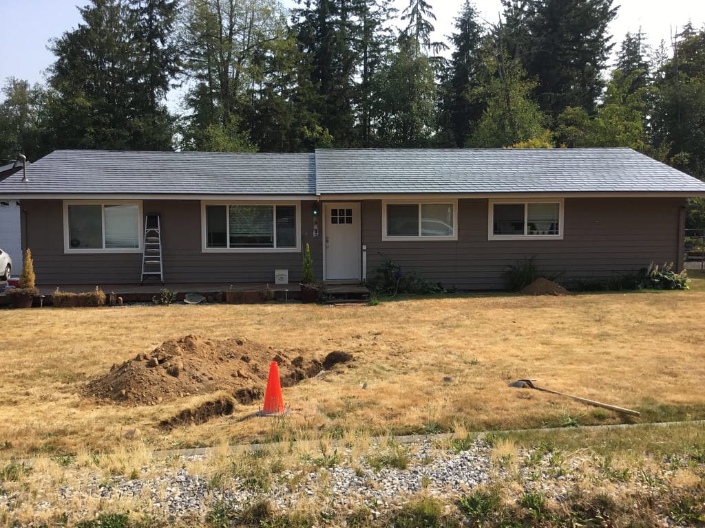 Musket Grey Interlock Slate aluminum roof on a grey ranch-style home with a metal roof among evergreen, Bonney Lake, Washington
