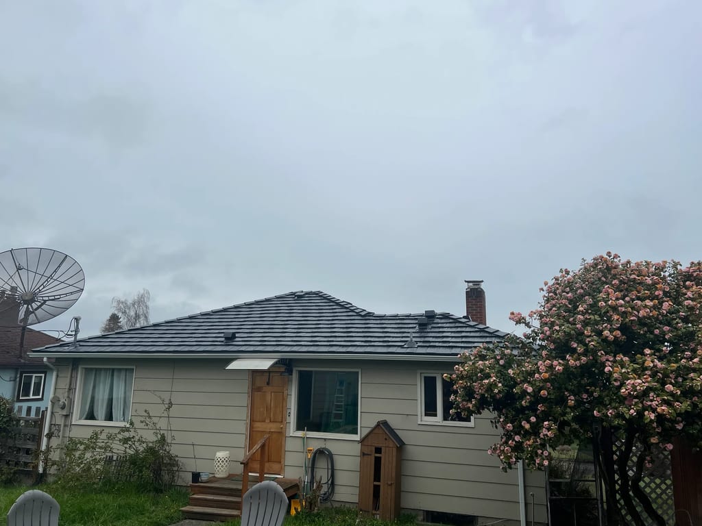 Black Interlock Shake aluminum roof on a beige one-storey home with dormers and a large tree, Port Angeles, Washington