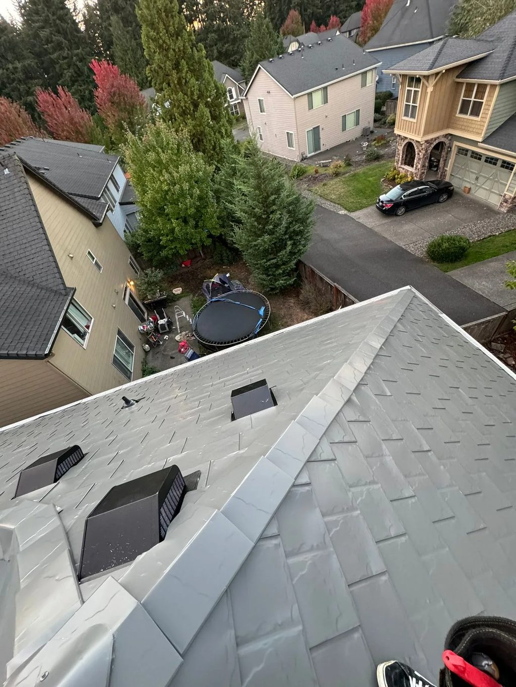 Musket Grey Interlock Slate aluminum roof being installed on a two-storey house with a metal roof in a suburban, Vancouver, Washington