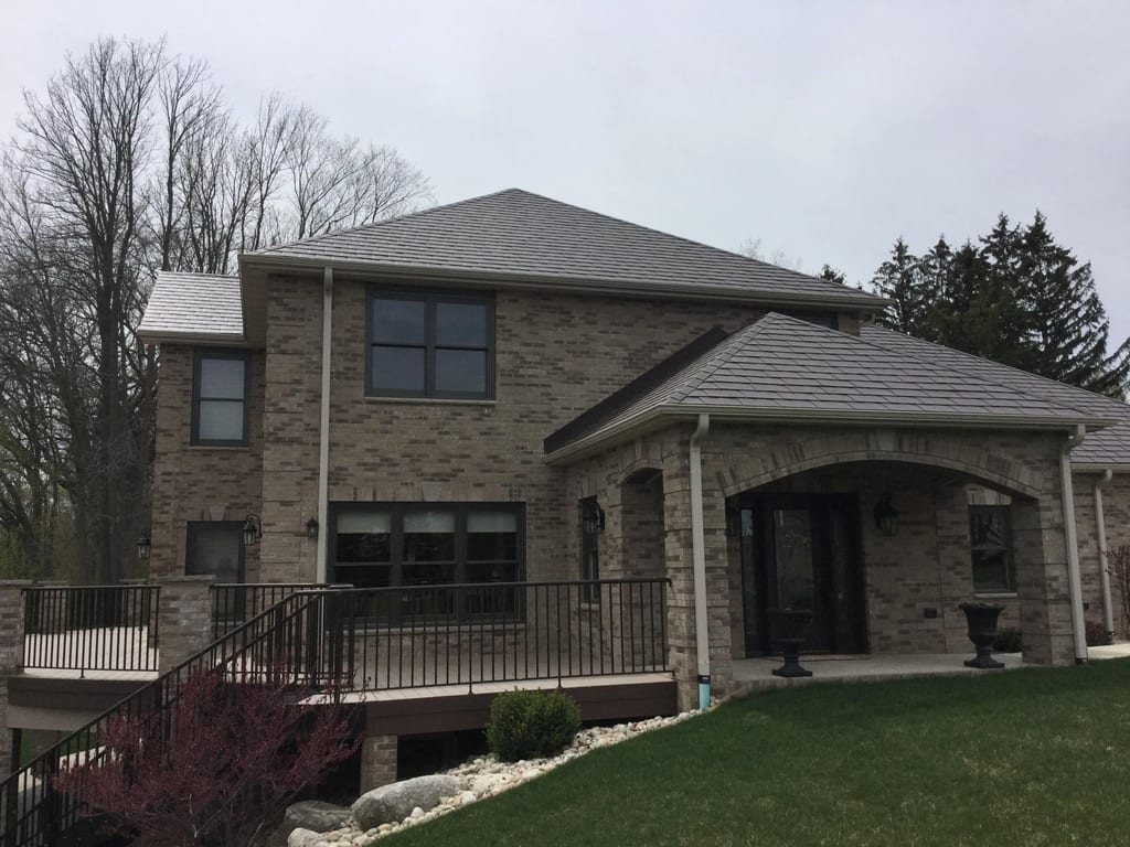 Colonial Brown Interlock Slate aluminum roof on a brown two-storey home with a metal roof and stone facade, Horicon, Wisconsin