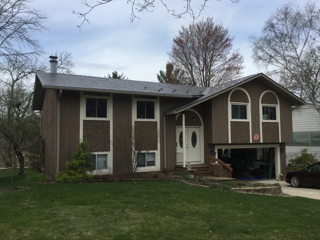 Weathered Interlock Slate aluminum roof on a brown single-storey home with a metal roof among tall, Madison, Wisconsin