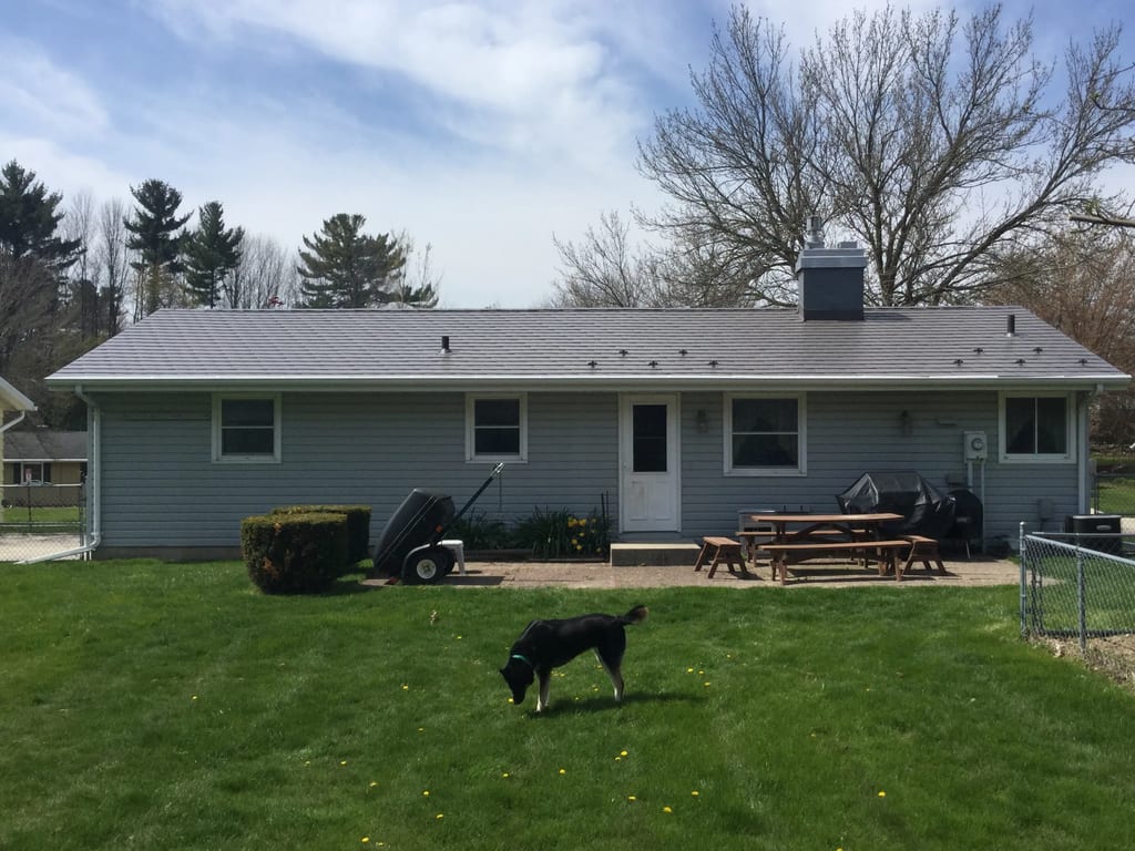 Weathered Interlock Slate aluminum roof on a gray ranch home with a metal roof among green grass, Sheboygan, Wisconsin
