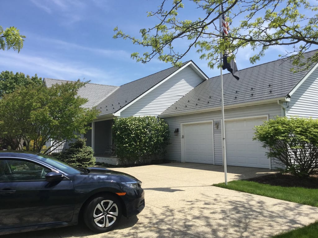 Tudor Brown Interlock Slate aluminum roof on a white Tudor home with dormers by a lake, Burlington, Wisconsin
