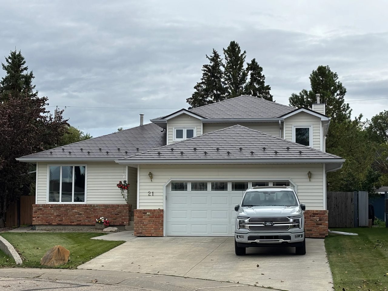 Tudor Brown Interlock Slate aluminum roof on a Tudor-style house with a brown roof in a rural area, Devon, Alberta