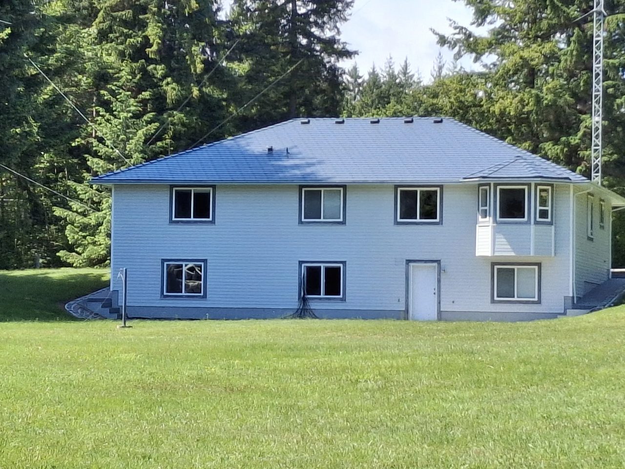 Deep Charcoal Interlock Slate aluminum roof on a white modern home with a metal roof in a forested rural, Courtenay, British Columbia