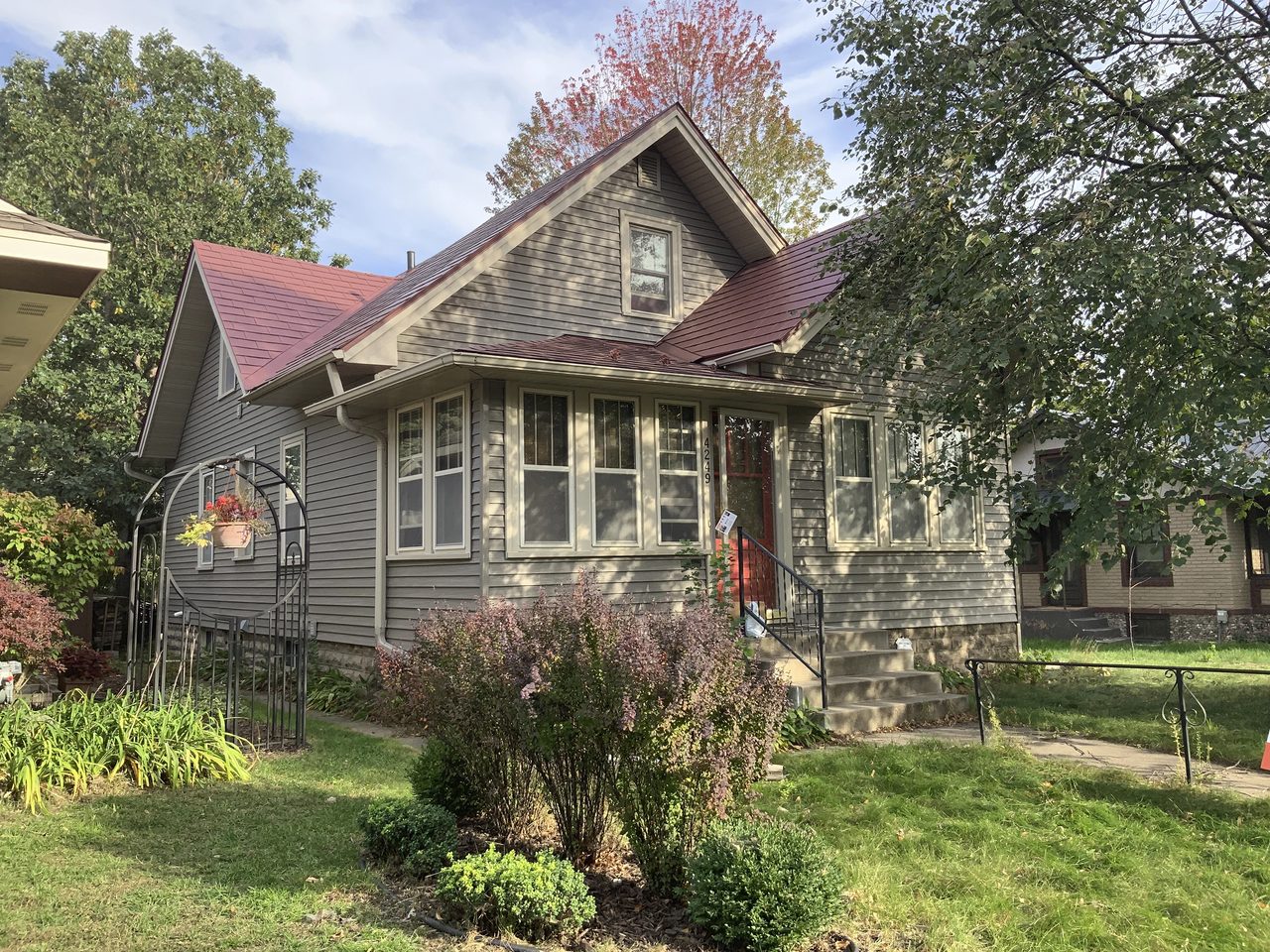 1.5-story Craftsman home in Minneapolis with a tile-red Interlock aluminum slate roof, front dormer, bay windows, and red entry door.