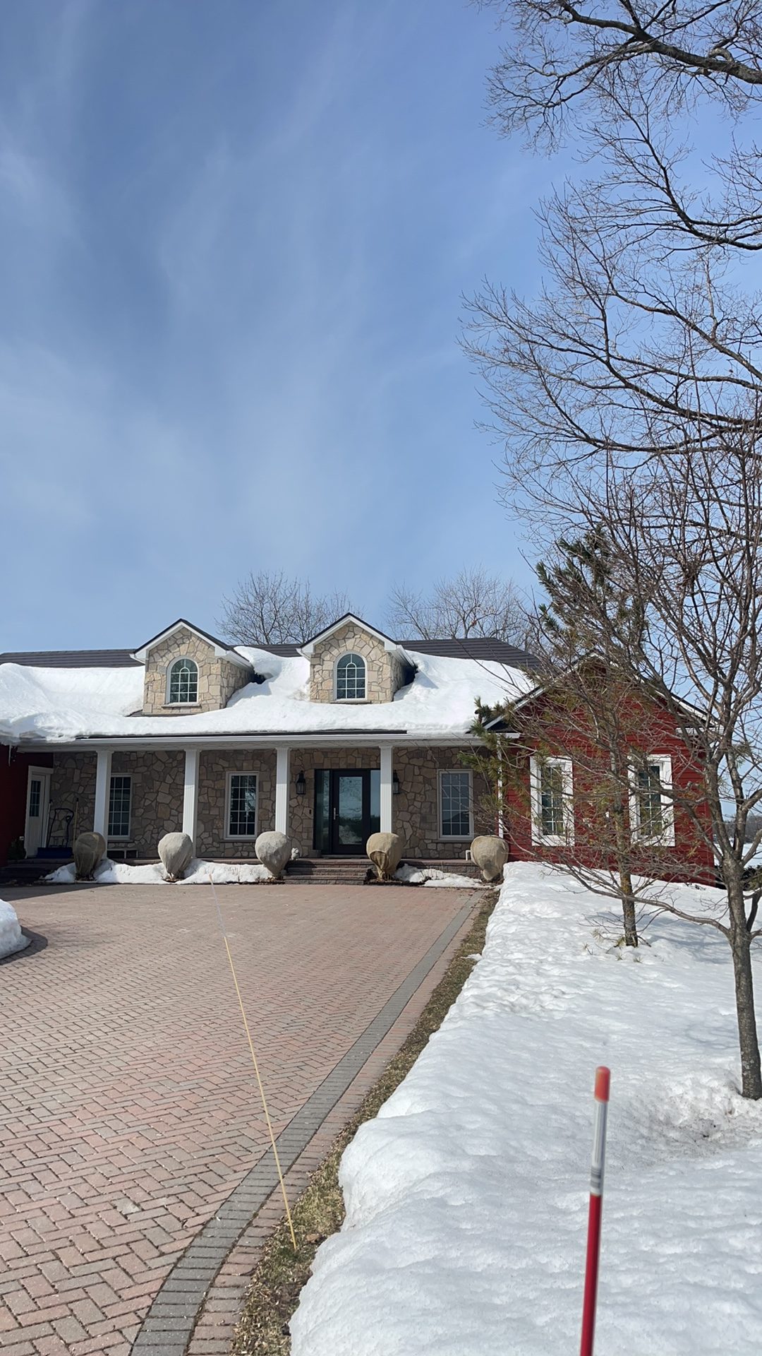 Tudor Brown Interlock aluminum slate roof with twin dormers on a 1.5-storey stone Colonial home in Orillia, ON, photographed in winter.