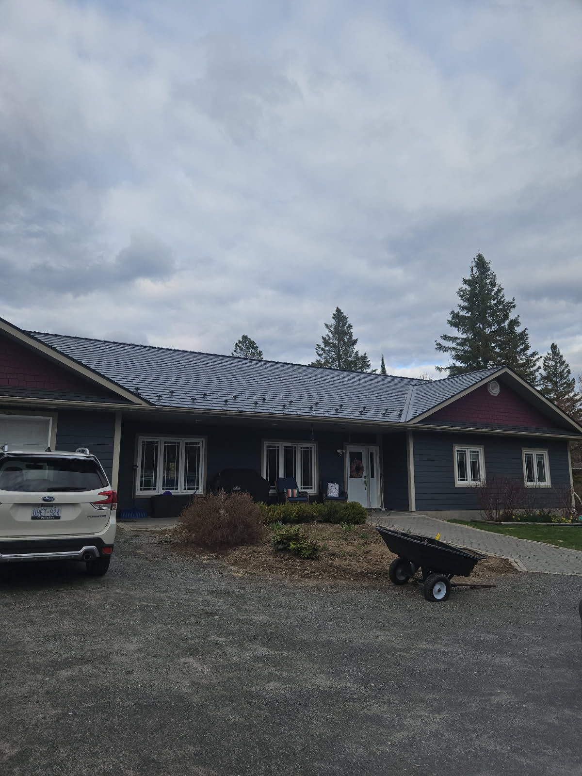 Front elevation of a single-storey ranch home in Sudbury, ON featuring Interlock deep charcoal cedar shingle aluminum metal roofing with snow guards.