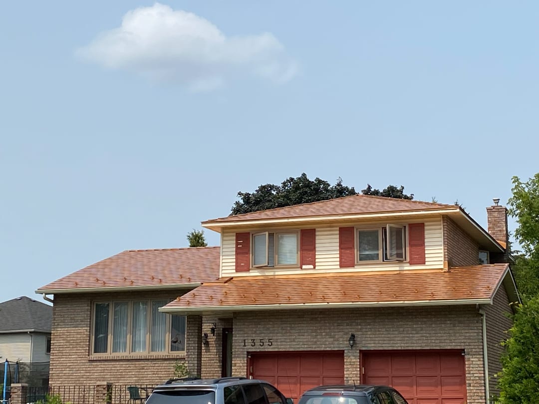 Two-storey Colonial brick home at 1355 with Interlock Copper Penny aluminum slate metal roof, red shutters, and double garage in Gloucester, ON.