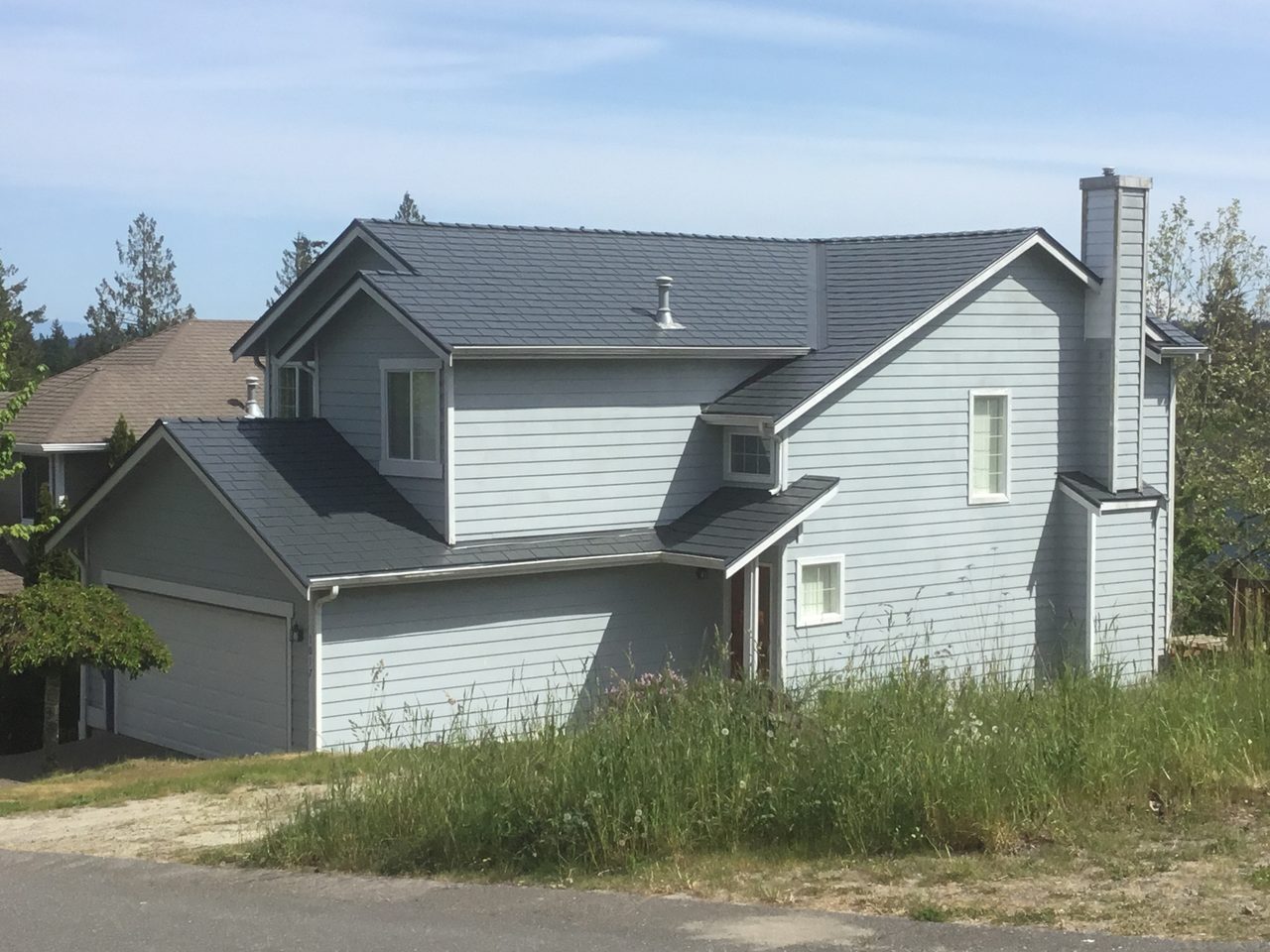 Two-story craftsman home in Silverdale, WA featuring Interlock aluminum slate roofing in Deep Charcoal, with dormer, chimney, and complex multi-gable roof.