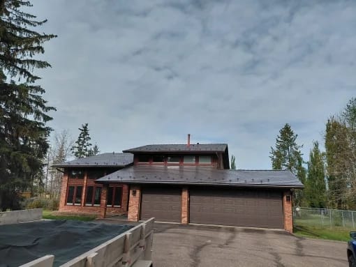 Tudor Brown Interlock Slate aluminum roof on a Tudor brown metal roof on a two-storey home in the woods, Sturgeon County, Alberta