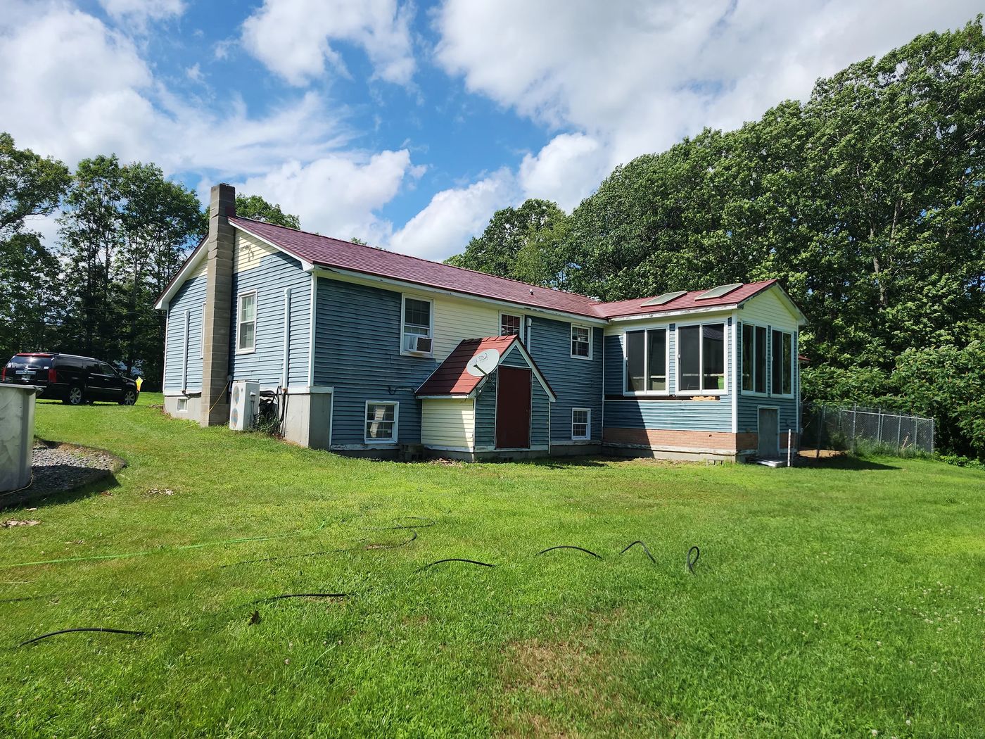 Tile Red Interlock Slate aluminum roof on a ranch-style home with a metal roof in a forested rural, Lebanon, Maine