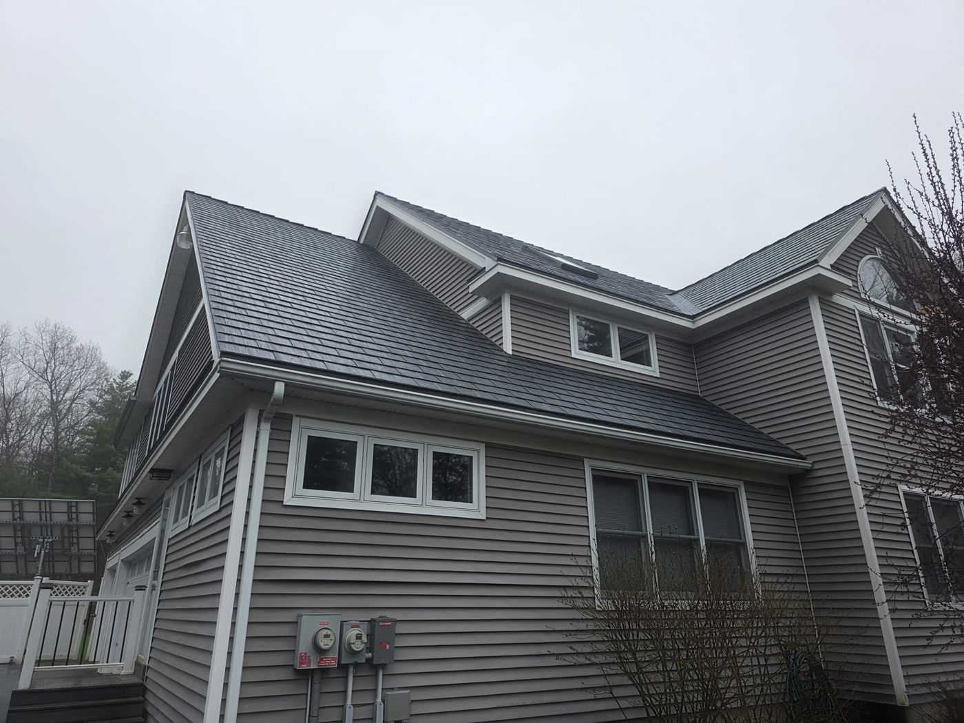 Two-story home in Pelham NH featuring Interlock deep charcoal aluminum slate metal roofing with dormers, valleys, and white trim accents.