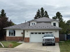 Tudor Brown Interlock Slate aluminum roof on a Tudor-style house with a brown roof in a rural area, Devon, Alberta