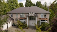 Tudor Brown Interlock Slate aluminum roof on a two-storey Tudor home with dormers among tall trees, Surrey, British Columbia