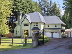 Deep Charcoal Interlock Slate aluminum roof on a beige two-storey home with dormers among tall pines, Bowser, British Columbia