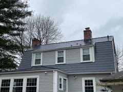 Two-story Colonial home in Walpole, MA with a deep charcoal Interlock aluminum slate mansard roof, two brick chimneys, and three dormers.