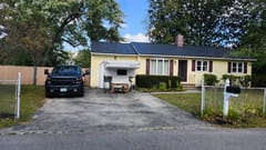 Single-story ranch home in Bedford, NH featuring a new black Interlock aluminum slate metal roof with dark gable profile and brick chimney.