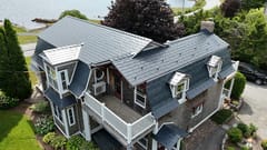 A colonial style home with a grey metal roof and white trim