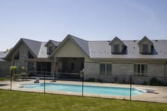 Rear elevation of a large Craftsman-style home in Guelph, ON featuring Interlock Musket Grey cedar shingle metal roofing with multiple dormers and louvered vents.